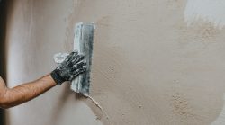 Male,Builder,In,Work,Overalls,Plastering,A,Wall,Using,A